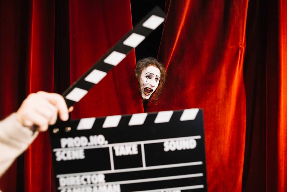 ביי פוסט צילום freepik human-hand-holding-clapperboard-front-male-mime-artist-performing-red-curtain